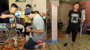 SYAFIQ Redzuan memasang kaki palsu pada Muhammad Daniel Haikal, sekali gus membolehkan remaja itu berjalan tanpa menggunakan tongkat di rumahnya di Kampung Batu Lapan Lepar, Kuantan. FOTO Mohd Rafi Mamat